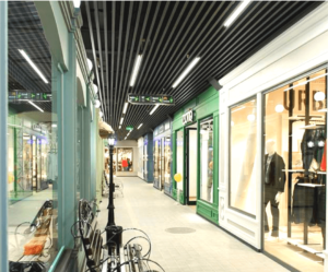Contemporary Mall Corridor Design Modern shopping mall corridor with dark matte metal slats on the ceiling, linear LED lights, and stylish storefronts displaying fashionable items.