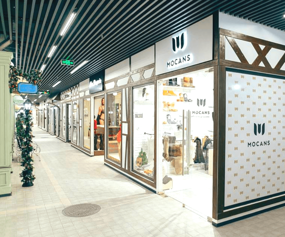Кубообразный потолок Modern shopping mall corridor with dark matte metal slats on the ceiling, linear LED lights, and stylish storefronts displaying fashionable items.